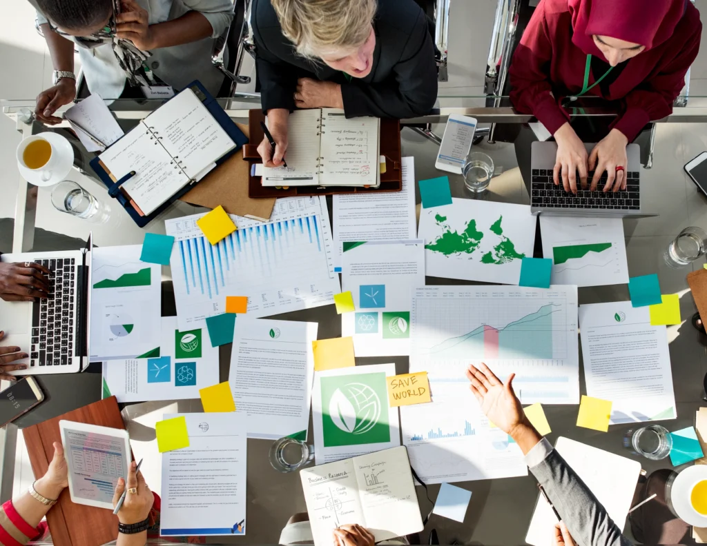 Una mesa repleta de reportes, mapas y gráficos refleja el trabajo analítico que requiere establecer metas alineadas con la SBTI en una organización.