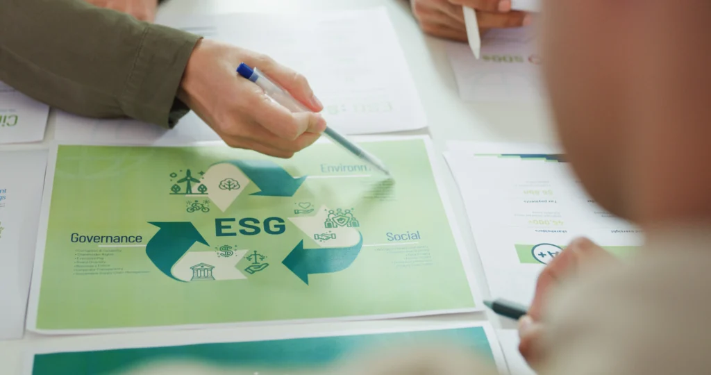 Una mano señala un gráfico impreso con íconos de medio ambiente, responsabilidad social y gobernanza, durante la revisión de Reportes ESG.
