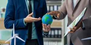 Vista de una persona sosteniendo un mundo, mientras la otra está sosteniendo una placa con los documentos necesarios para la evaluación EcoVadis.