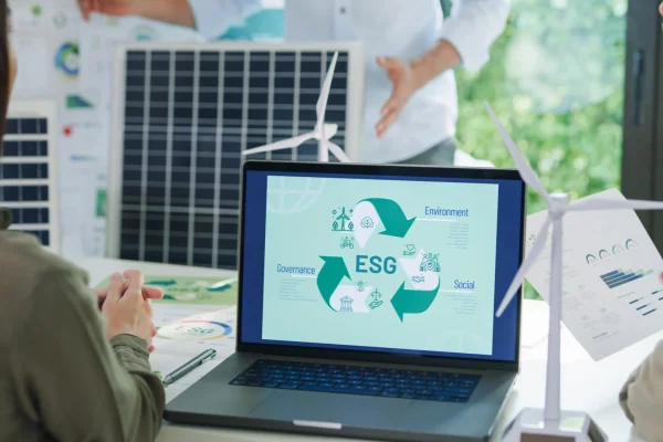 Computadora con gráfico sobre criterios ESG, mientras una persona señala datos relacionados con energías limpias, destacando herramientas como Workiva ayudan a integrar informes sostenibles y financieros.